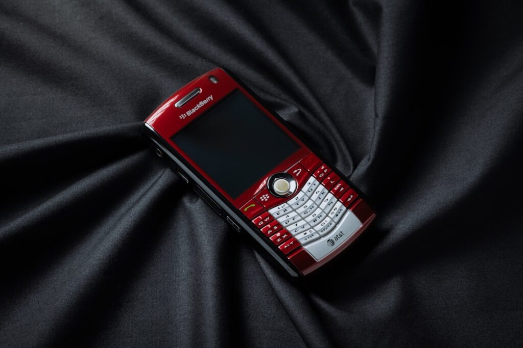 A red and white cell phone laying on a black cloth